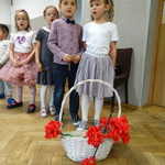 dzieci z grupy podróżnicy śpiewają piosenkę a przed nimi stoi kosz z kwiatami z bibuły