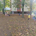 Dzieci z grupy Podróżnicy biegają po placu w poszukiwaniu liści kasztanowca