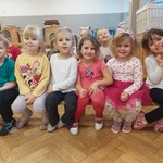 Dzieci z grupy Tajemniczy Ogród siedzą na ławce i oglądają występ