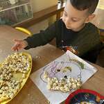 Chłopczyk wykleja pracę popcornem
