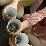 Dzieci trzymają papierowe kubeczki wypełnione pociętymi karteczkami