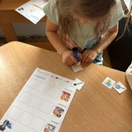 Dziewczynka przykleja elementy na kartę pracy
