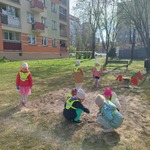 Dzieci zbierają śmieci na placu przed blokiem