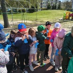 Dzieci zakładają gumowe, niebieskie rękawiczki do sprzątania