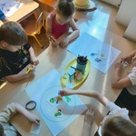 Dzieci siedzą podczas zajęć przy stoliku