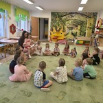 Dzieci siedzą w kole i słuchają bajki czytanej przez mamę