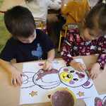 Chłopiec i dziewczynka malują farbami obrazek misia